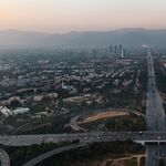 A stunning aerial view of Islamabad with highways, buildings, and mountains at dusk.