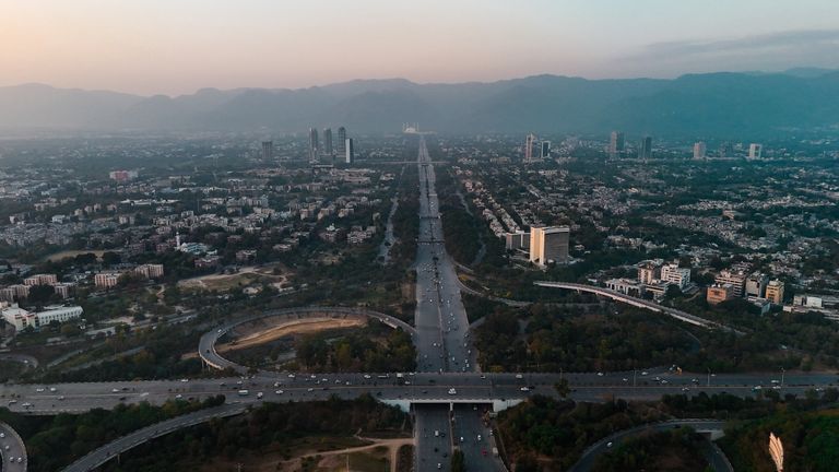 A stunning aerial view of Islamabad with highways, buildings, and mountains at dusk.